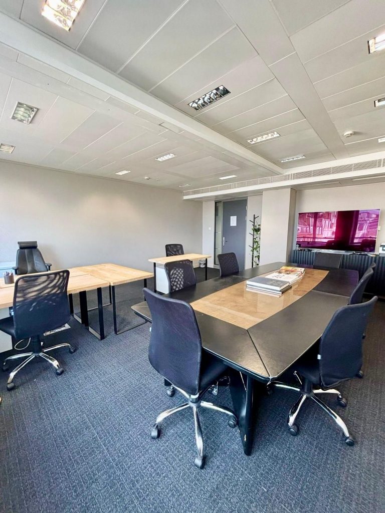 Spacious private office at 33 Cavendish Square featuring a modern conference table, executive desk, ergonomic chairs, carpet flooring